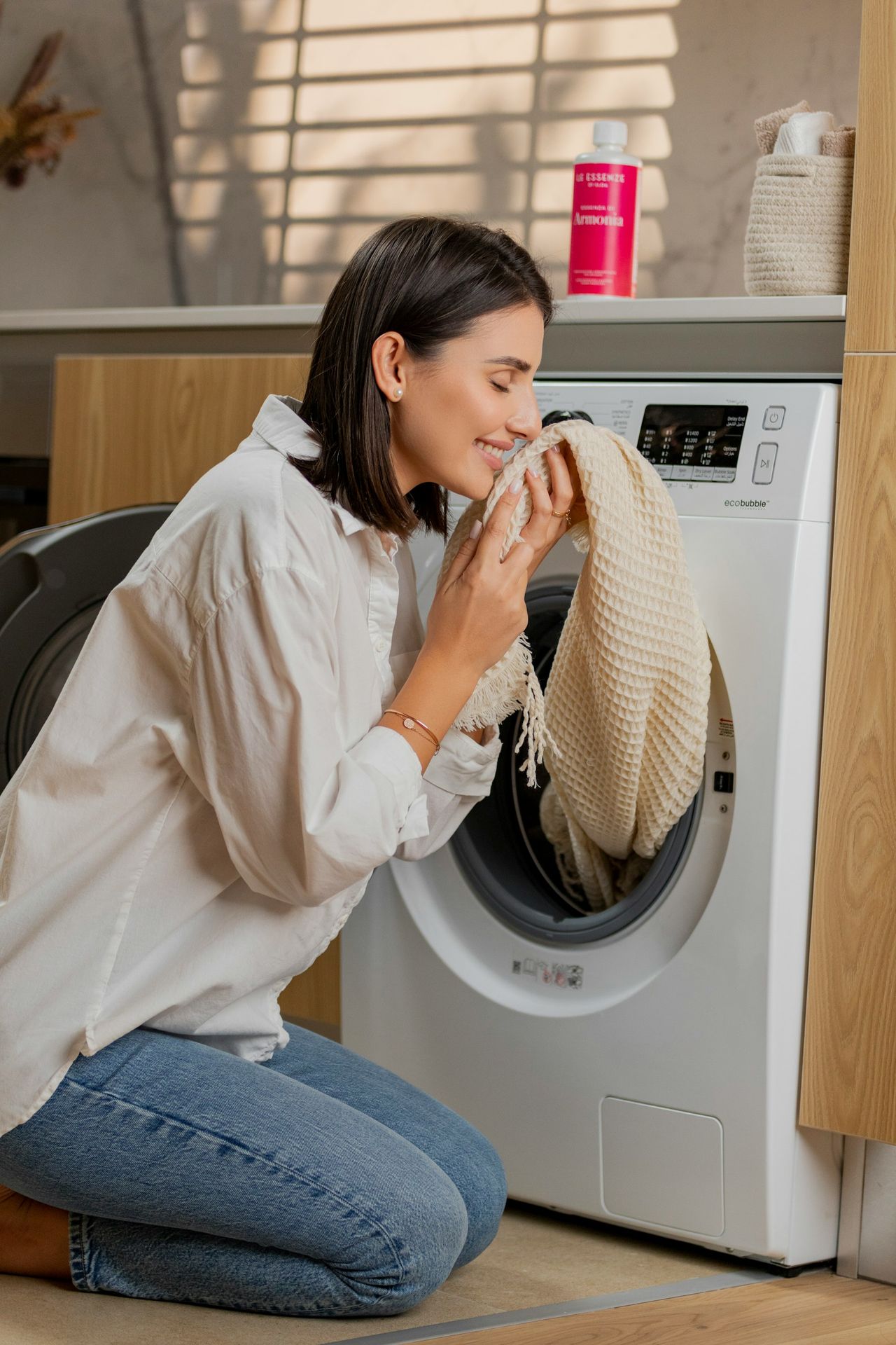 một người phụ nữ đang ngồi trên sàn trước máy giặt